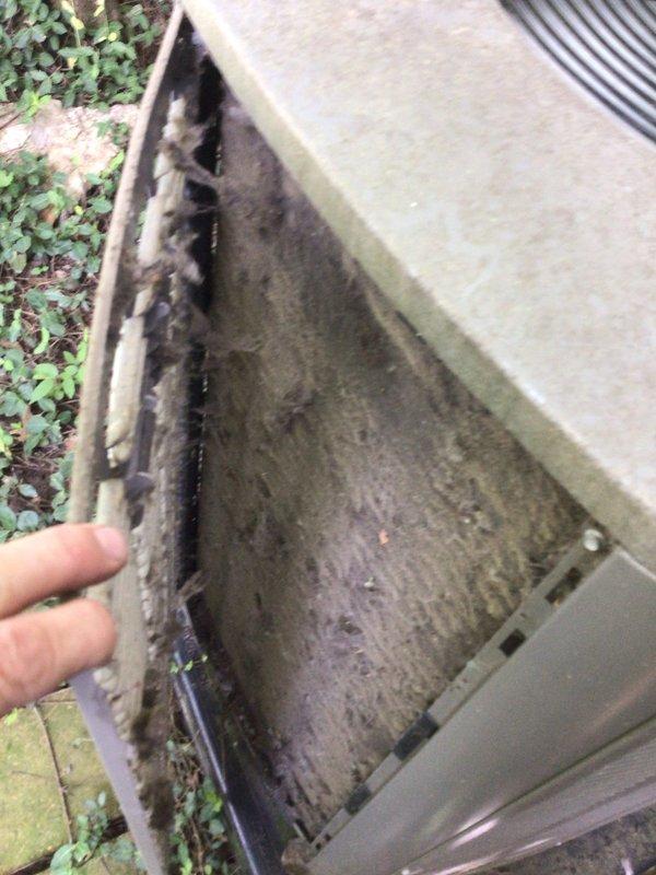 Responded to no-cooling call on residential air conditioning system less than 10 years old located in backyard. Upon arrival, discovered outdoor condensing unit experiencing severe biological contamination with extensive algae and mold growth throughout interior cabinet, indicating prolonged moisture exposure and drainage issues. Interior components heavily affected by organic buildup on walls, base, and mechanical parts. Investigation revealed secondary water damage issue inside residence, with significant water staining and tracking patterns observed on utility room floor near laundry area, suggesting possible condensate drain line failure or overflow condition. Performed thorough inspection of affected condensing unit, documenting contamination levels. Assessed drainage system integrity and identified root cause of cooling system failure related to biological obstruction and moisture intrusion. Unit required comprehensive cleaning and remediation to restore proper operation and prev