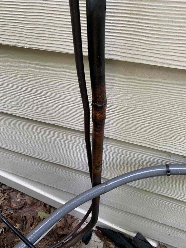 Responded to no cooling complaint on recently installed Trane air conditioning system. Upon inspection, discovered severely corroded refrigerant lines with significant internal and external deterioration, including visible debris buildup inside copper piping. Documented compromised line set condition with inspection mirror to verify internal damage and photographed extensive corrosion on exterior refrigerant lines and conduit connections, which was causing refrigerant leak and loss of cooling capacity.