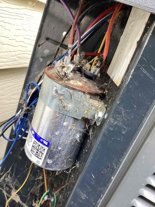 Responded to no cooling complaint with indoor temperature at 89 degrees. Upon inspection of Unit 10 located in side yard, found failed dual run capacitor with severe corrosion and heavy debris accumulation around terminals and connection points. Capacitor showed visible rust, material degradation, and oxidation indicating moisture exposure and age-related failure. Replaced defective capacitor with new unit per manufacturer specifications. Cleaned terminal connections and secured all wire connections. Tested system operation, verified proper amperage draws on compressor and condenser fan motor. Unit now cooling properly with normal operating pressures and temperatures restored.