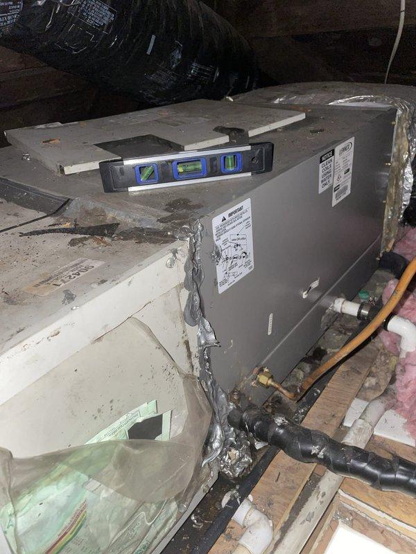Responded to service call for air conditioner leaking water into bathroom. Upon inspection, found HVAC unit in attic space was not level, causing condensate drain pan to overflow and leak through ceiling into bathroom below. Leveled unit using appropriate shimming techniques and verified proper pitch for condensate drainage. Inspected drain line for blockages, cleared primary drain line, and tested system operation to confirm water was draining correctly. Checked secondary drain pan and overflow switch functionality. Verified no further water leakage occurring. System restored to proper operation with condensate draining as designed.