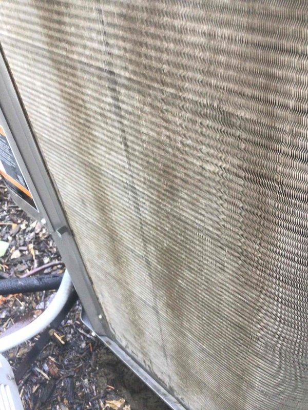 Responded to no-cool complaint on 13-year-old upstairs system. Upon arrival, found outdoor condensing unit with heavily soiled condenser coil exhibiting significant dirt accumulation, organic growth, and environmental debris buildup restricting airflow. Coil fins showed brownish-green staining and dust accumulation on both exterior surfaces and underside of unit. Documented equipment condition with photos showing extent of contamination affecting heat transfer efficiency and system performance.