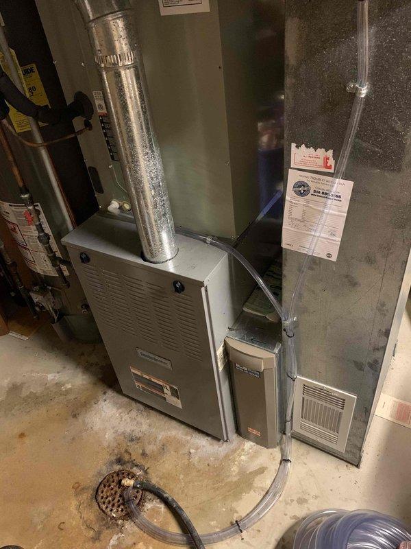 Responded to service call for water leaking from top of air conditioning unit located in basement. Upon inspection, found excessive condensation and water accumulation on evaporator coil assembly and drain pan components. Identified clogged condensate drain line as primary cause of overflow condition. Cleared obstruction from drain line, verified proper drainage flow, and tested system operation. Unit cooling properly with condensate now draining correctly through cleared line.