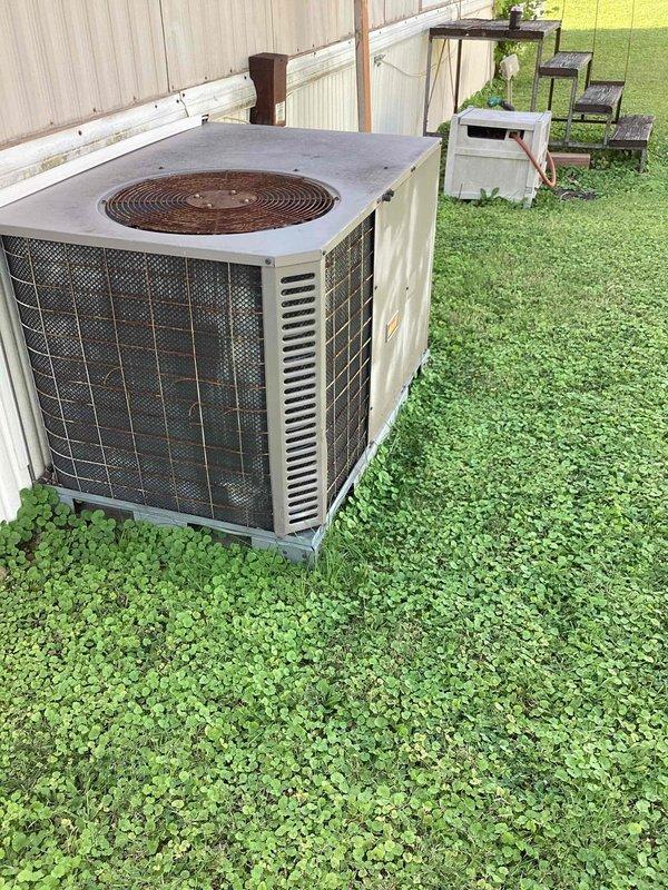Responded to no cooling complaint on a 10+ year old self-contained outdoor AC unit located in backyard. Upon arrival, performed diagnostic evaluation of the condenser unit, which showed visible signs of weathering and corrosion on the top fan grille. Conducted temperature and system performance measurements using digital diagnostic equipment on the condenser coil fins. Initial assessment indicated potential refrigerant deficiency as reported, though further testing was required to determine if leak repair or other mechanical issues were contributing to the cooling failure. Unit had been experiencing extended operational problems. Documented equipment condition with photographs showing the outdoor condenser on concrete pad and close-up diagnostic work on the coil assembly. Customer advised of findings and repair options to restore proper cooling function.