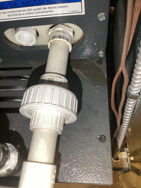 Responded to callback for ongoing water leak beneath furnace in basement. Upon inspection, found condensate drain line assembly showing signs of moisture accumulation and residue buildup around PVC coupling connection. Identified dust and debris accumulation on equipment surfaces, indicating potential drainage obstruction. Inspected drain pan, PVC drain piping, and connection fittings for proper slope and secure attachment. Verified drain line routing and trap configuration to ensure proper condensate removal from 10-year-old unit.