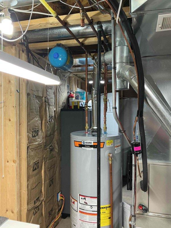 Installed a 50-gallon tall gas water heater with 3/4" pressure relief valve in residential basement utility area. Completed copper piping connections with brass fittings to main water supply lines, installed expansion tank mounted to ceiling joists with secure strapping, and verified all connections for proper operation. Material was ordered through Ferguson supply house under purchase order #1332285-001, and installation was performed in compliance with St. Charles County permit requirements.