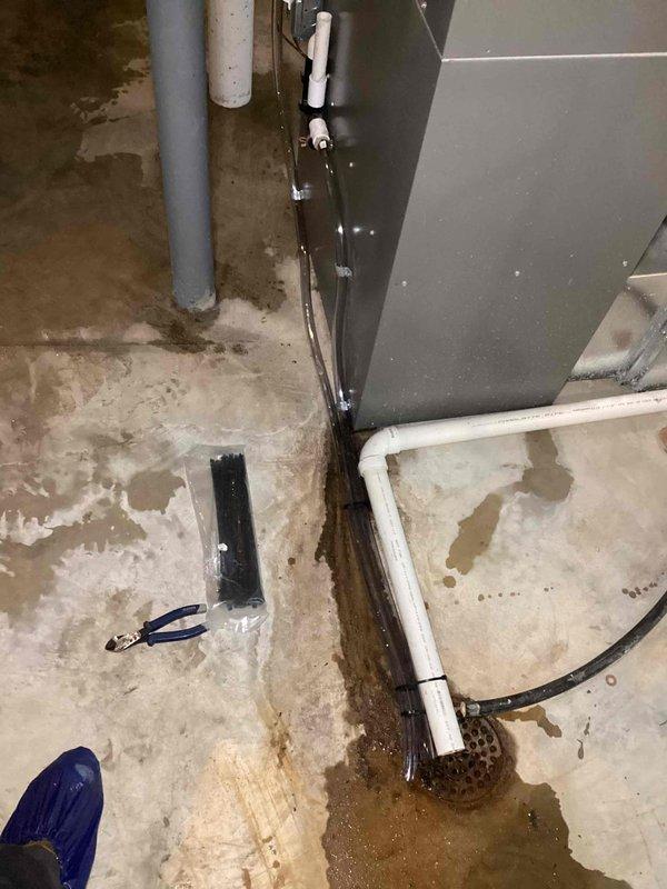 Responded to no-cool complaint on 11-year-old Lennox AC unit that had been serviced approximately one month prior for refrigerant leak and recharge. Upon arrival, discovered significant water flooding throughout basement mechanical room with standing water pooling around HVAC equipment. Inspected evaporator coil and drain system, identifying clogged condensate drain line as primary cause of water accumulation. Cleared blockage from condensate line using appropriate tools and verified proper drainage. Checked refrigerant levels and pressures on AC system, finding unit low on charge, indicating repeat leak issue as initially reported. Performed leak detection on refrigerant circuit, locating active leak at evaporator coil connection point. Due to age of unit and recurring leak pattern at same location, recommended evaluation of coil replacement versus system replacement options. Extracted standing water from floor area to prevent further damage to surrounding equipment and structure. Adv