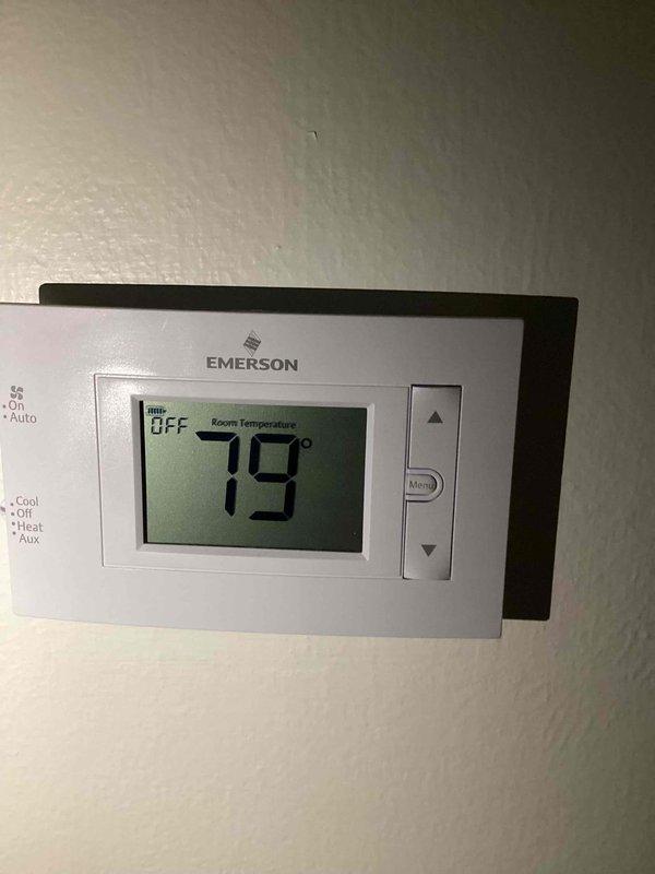 Responded to no cooling complaint with frozen evaporator coil. Upon arrival, confirmed thermostat set to OFF position with room temperature reading 79°F. Inspected outdoor condensing unit and found unit operational but experiencing reduced airflow condition leading to coil freeze-up. Documented system condition with photos of thermostat display and outdoor unit placement. Issue differs from previously scheduled estimate appointment. Recommended allowing coil to thaw completely before further diagnostics to determine root cause of freezing condition, which may include low refrigerant charge, restricted airflow from dirty filter or blocked return, or blower motor malfunction.