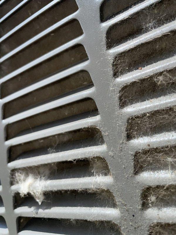 Responded to no cooling complaint on residential air conditioning system. Upon arrival, found outdoor condenser unit operational but severely restricted return airflow due to heavy dust, lint, and debris accumulation in return air grille. Documented excessive buildup blocking airflow through vent openings, which was causing reduced system performance and insufficient cooling. Inspected outdoor condenser unit and confirmed proper operation with no visible mechanical issues. Advised customer that clogged return air grille was primary cause of cooling deficiency and recommended immediate cleaning of all return air vents and replacement of air filter to restore proper system airflow and cooling capacity.