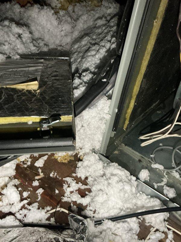 Responded to service call for blank thermostat screen on residential HVAC unit located in family room, less than 10 years old. Upon inspection of attic-mounted air handler, discovered severe frost and ice buildup throughout the interior compartment, covering evaporator coil, housing walls, and drain pan. Heavy crystalline frost accumulation indicated restricted airflow causing coil to freeze. Documented conditions with photos showing extensive ice formation on all internal components and metallic surfaces. Inspected ductwork and condensate drain system for proper operation. Confirmed unit is not servicing a conditioned attic space as part of initial diagnostic assessment.