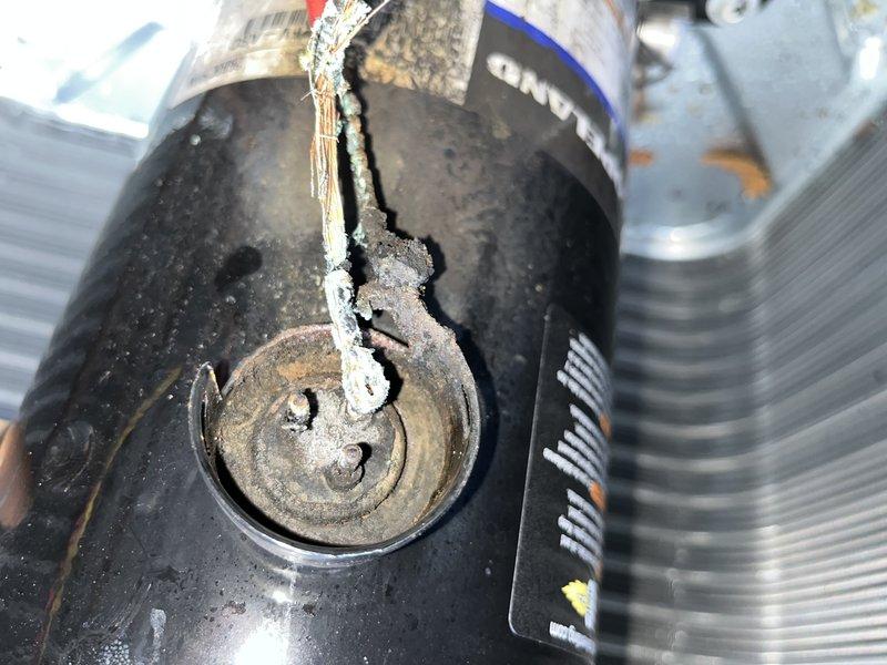 # HVAC Service Call Completion Report

Responded to callback for reported compressor failure on air conditioning system. Upon arrival, confirmed complete compressor failure with catastrophic internal damage. Visual inspection revealed extensive electrical terminal corrosion with green and white oxidation buildup at connection points, indicating prolonged moisture intrusion. Compressor housing exhibited severe external deterioration, rust staining, and compromised wiring connections.

Assessment identified failed run capacitor with vertical cracking along casing and separated insulation material, contributing to system failure. Capacitor damage rendered component non-functional and required immediate replacement. Collected payment and completed system replacement per customer authorization. Advised customer to shut off AC unit and operate fan only until repairs were finalized to prevent further damage. Documented equipment condition with photographic evidence showing corrosion damage, f