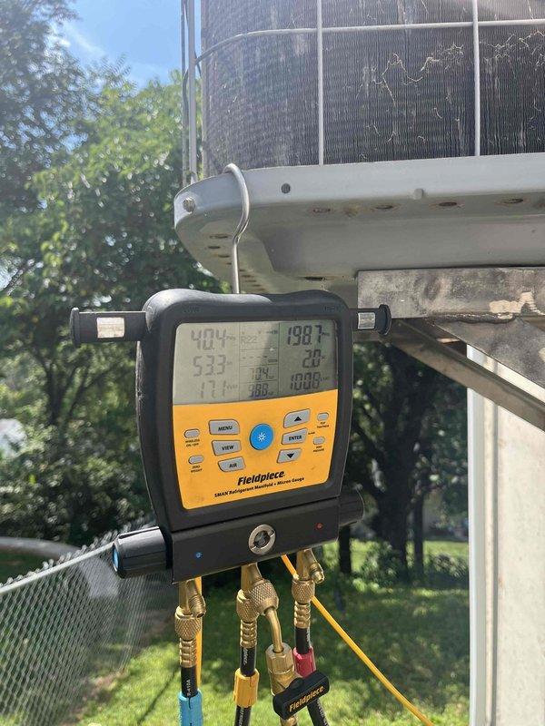 Responded to no cooling complaint on residential unit over 10 years old located in side yard. Upon arrival, found evaporator coil frozen over as reported. Advised customer to turn system off and leave fan on to thaw coil. Connected Fieldpiece digital manifold gauges to measure system pressures and temperatures on outdoor condenser unit. Performed electrical diagnostics using Fluke clamp meter to check amperage draw and verify proper power supply to components. Assessed refrigerant charge levels and system operation. Documented findings with photos of diagnostic equipment readings and electrical measurements. Unit required thawing period before further testing could be completed to determine root cause of freezing condition, which could include low refrigerant charge, restricted airflow, or faulty components.