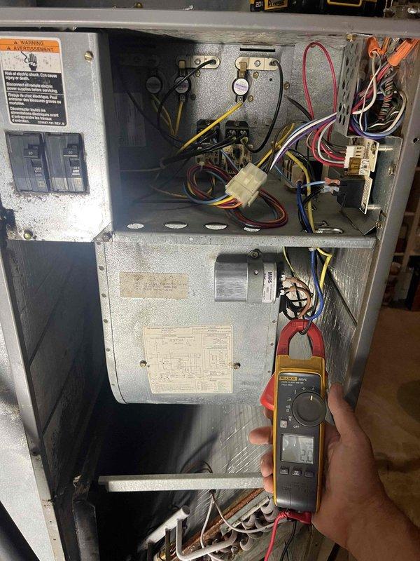 Responded to no cooling complaint on residential unit over 10 years old located in side yard. Upon arrival, found evaporator coil frozen over as reported. Advised customer to turn system off and leave fan on to thaw coil. Connected Fieldpiece digital manifold gauges to measure system pressures and temperatures on outdoor condenser unit. Performed electrical diagnostics using Fluke clamp meter to check amperage draw and verify proper power supply to components. Assessed refrigerant charge levels and system operation. Documented findings with photos of diagnostic equipment readings and electrical measurements. Unit required thawing period before further testing could be completed to determine root cause of freezing condition, which could include low refrigerant charge, restricted airflow, or faulty components.