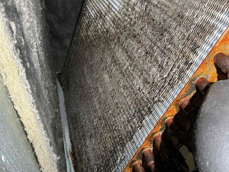 Responded to service call for air conditioning unit not activating when thermostat temperature was adjusted. Upon arrival, inspected 10-year-old ground-level outdoor condensing unit located on side of property. Performed visual assessment of condenser coil, which showed moderate dust and debris accumulation between fins, and noted corrosion on mounting hardware and frame components. Examined accessible ductwork in utility area, observing significant dust buildup on flexible aluminum ducting. System evaluated for electrical connectivity and thermostat communication issues to determine cause of activation failure.