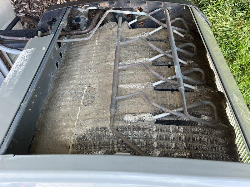 Responded to service call for unit not cooling properly. Upon inspection, found evaporator coil heavily contaminated with dust, dirt, and debris accumulation restricting airflow through the aluminum fins. Removed access panel and documented coil condition showing significant buildup and discoloration across the coil surface. Refrigerant lines showed surface oxidation but no visible damage. Unit located on ground level at side of property. Performed system evaluation and documented findings with photographic evidence. Recommended thorough coil cleaning to restore proper airflow and system efficiency.