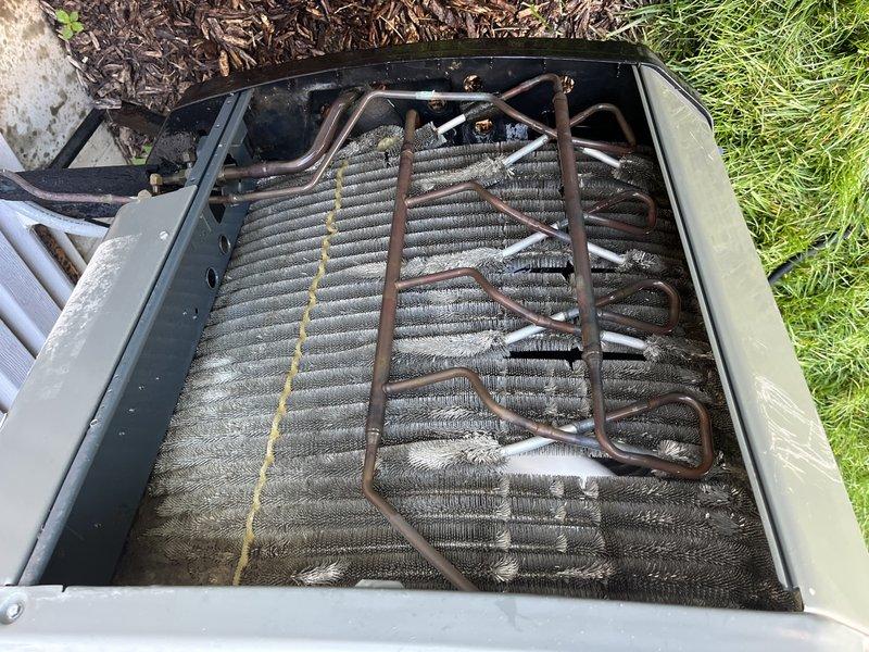 Responded to service call for unit not cooling properly. Upon inspection, found evaporator coil heavily contaminated with dust, dirt, and debris accumulation restricting airflow through the aluminum fins. Removed access panel and documented coil condition showing significant buildup and discoloration across the coil surface. Refrigerant lines showed surface oxidation but no visible damage. Unit located on ground level at side of property. Performed system evaluation and documented findings with photographic evidence. Recommended thorough coil cleaning to restore proper airflow and system efficiency.