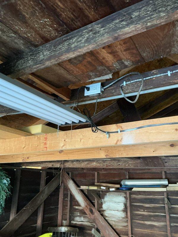 Completed electrical estimate for garage fixture installation in attic space with exposed structural framework. Assessment included evaluation of existing fluorescent lighting, conduit routing along wooden beams, junction box placement, and determination of materials required for fixture upgrades. Documented current wiring configuration and structural mounting points for fixture installation planning.