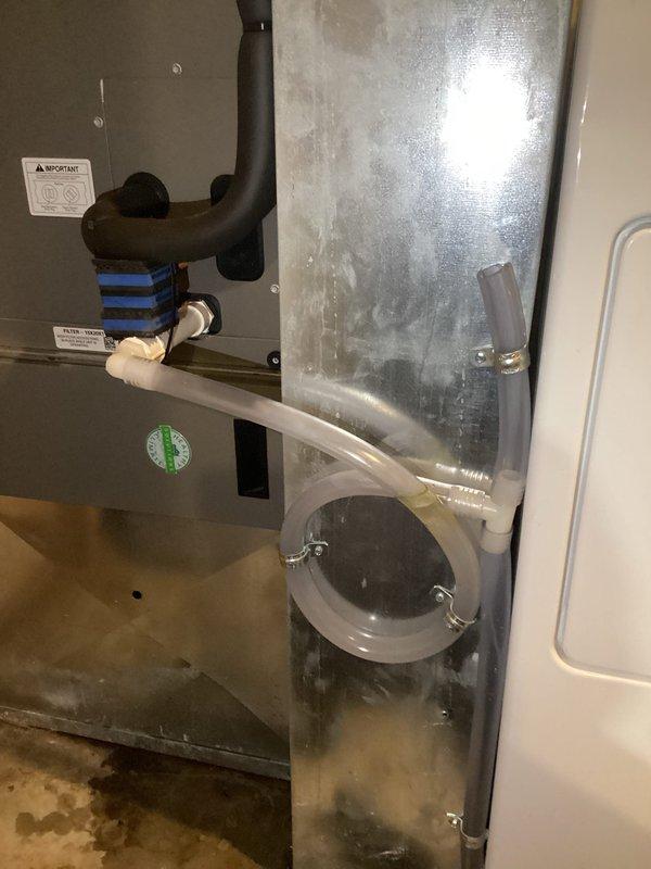 Responded to water leak complaint at air handler unit in laundry room. Upon arrival, found visible water pooling on floor beneath unit and saturated air filter. Inspection revealed leak originating from filter housing area where filter slot meets top section of unit. Examined condensate drain system, including P-trap and drain line connections visible in equipment area. Checked refrigerant lines, brass fittings, and copper tubing for signs of condensation or leakage. Verified unit was recently installed in March and still under first-year warranty coverage. Documented internal components, filter housing labeled for 15x20x1 filter, ductwork connections, and drain trap assembly with photographs for warranty claim processing. Identified source of leak at filter compartment interface requiring warranty service or manufacturer involvement for proper resolution of defect in newly installed equipment.