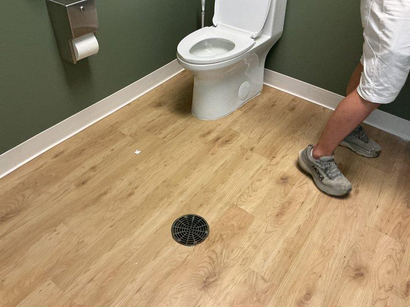 Responded to main sewer line clog at commercial cosmetic facility. Upon arrival, accessed building's main drain cleanout located in restroom area with floor drain. Successfully cleared blockage in main sewer line, restoring proper drainage throughout the building. System tested and verified operational. Documentation photos taken of work area and drain access point.
