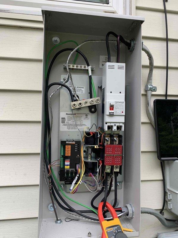 Responded to service call for standby generator that was running test cycles but not producing power output. Upon arrival, inspected the backyard-mounted generator system and associated transfer switch panel. Performed diagnostic testing using clamp meter to verify absence of power generation during simulated test cycle. Identified issue with generator control panel and transfer switch operation preventing power transfer to the electrical distribution system despite engine operation. Inspected circuit breakers, bus bar connections, and generator disconnect switch for proper operation and secure connections. Documented existing conditions of electrical panel components including 50-amp and 60-amp breakers, control wiring, and safety disconnect mechanisms. Reviewed warning labels and confirmed proper safety protocols. Provided assessment of necessary repairs to restore full generator functionality and power transfer capability.