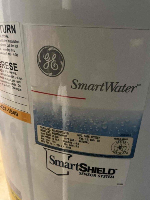 Removed and replaced a failed 25-year-old 50-gallon gas water heater located in the basement with a new State brand 50-gallon gas tall water heater. Disconnected existing gas supply line, water supply connections, and venting system from the old GE SmartWater unit manufactured in 2007. Installed new State water heater with proper copper water line connections, brass shutoff valves with red and blue handles for hot and cold water isolation, and appropriate gas line connections. Configured plumbing connections at top of unit including both vertical and horizontal copper pipe runs with compression fittings. Installed PVC venting system and ensured proper clearances around unit. Verified all connections for leaks, tested gas line integrity, and confirmed proper operation of the SmartSHIELD sensor system and all safety features before returning unit to service.