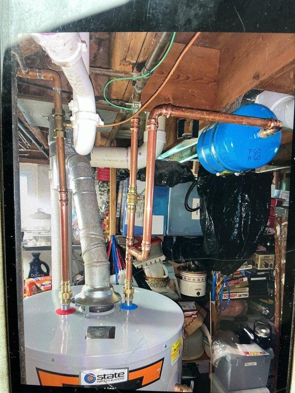 Removed and replaced a failed 25-year-old 50-gallon gas water heater located in the basement with a new State brand 50-gallon gas tall water heater. Disconnected existing gas supply line, water supply connections, and venting system from the old GE SmartWater unit manufactured in 2007. Installed new State water heater with proper copper water line connections, brass shutoff valves with red and blue handles for hot and cold water isolation, and appropriate gas line connections. Configured plumbing connections at top of unit including both vertical and horizontal copper pipe runs with compression fittings. Installed PVC venting system and ensured proper clearances around unit. Verified all connections for leaks, tested gas line integrity, and confirmed proper operation of the SmartSHIELD sensor system and all safety features before returning unit to service.