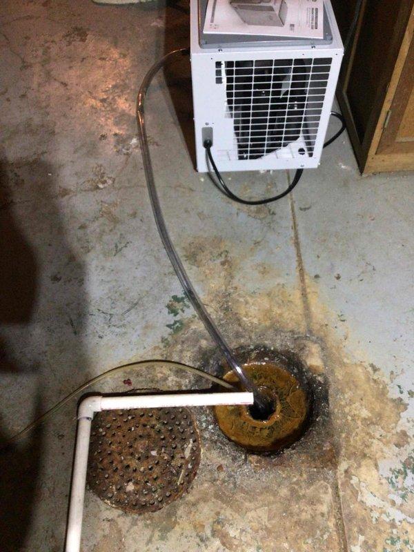 Installed portable dehumidifier unit in basement utility area and connected drainage hose to existing floor drain for condensate removal. Verified unit operation and proper drainage flow. System is functioning as designed to control humidity levels in the space.