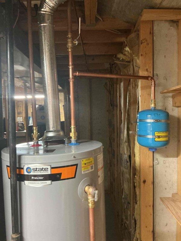 Installed a 40-gallon State ProLine commercial-grade gas water heater in basement utility area with complete copper piping connections, brass shut-off valves, and proper venting through metallic duct system. Connected unit to existing pressure tank system with appropriate compression fittings and integrated galvanized supply lines with copper distribution piping using brass transition fittings and ball valves for system isolation.
