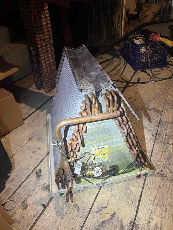 Completed evaporator coil replacement in attic-mounted air handling unit. Removed and disposed of failed coil exhibiting severe oxidation and corrosion on copper tubing. Installed new A-coil assembly with proper refrigerant line connections, reconfigured condensate drain system using 3/4" PVC union, six 90-degree elbows, drain pan fitting, and appropriate primer and flue components. System tested and operational upon completion.