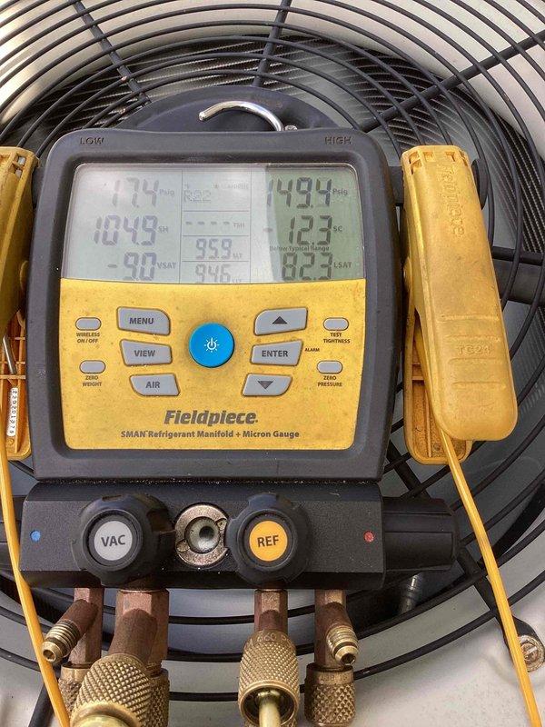 Responded to no-cool call on 10+ year old outdoor unit located at side of home. Upon arrival, customer reported AC unit had been freezing up and was shut off. Connected Fieldpiece SMAN refrigerant manifold with micron gauge to system for diagnostic testing. Performed pressure and temperature readings on refrigerant circuit to identify cause of freeze-up condition. Measurements indicated abnormal operating pressures consistent with restricted airflow or low refrigerant charge. Documented system conditions with diagnostic equipment showing multiple temperature and pressure values for further analysis and repair recommendations.