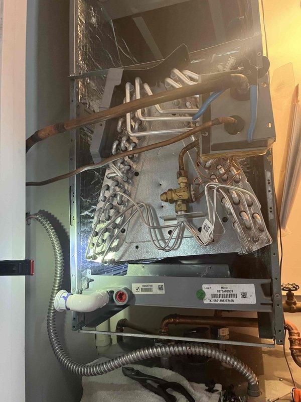 Returned to property to reinstall evaporator coil assembly after previous installation resulted in cross-threaded drain pan connection that caused damage to the original coil. Removed damaged coil from system and discarded per protocol since warranty could not be processed due to installation damage. Installed replacement evaporator coil obtained from supply house, ensuring proper alignment and secure connection of drain pan to prevent threading issues. Connected refrigerant lines to new coil assembly with proper torque specifications and verified all brass fittings were secure. Tested system operation to confirm heating and cooling functionality restored. Unit operational upon departure.