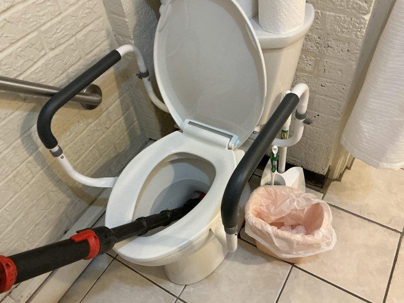 Responded to service call for reported toilet backing up in bathroom. Upon arrival, performed visual inspection of toilet and surrounding plumbing fixtures. Toilet was equipped with accessibility grab bars and appeared to be in clean condition with clear water in bowl. 

Assessed bathroom plumbing system including visible PVC drainage pipes and supply lines. Checked bathroom vanity sink with decorative porcelain basin and brass fixtures for any related drainage issues. Inspected floor-mounted shut-off valves and supply lines beneath vanity cabinet.

Tested toilet function and drainage flow. Plunger was available on-site for clearing potential blockages. Evaluated drainage system performance and identified source of backup issue. Performed necessary clearing procedures to restore proper toilet function and drainage. Verified all fixtures were operating correctly upon completion. Documented conditions with photographs for service records.