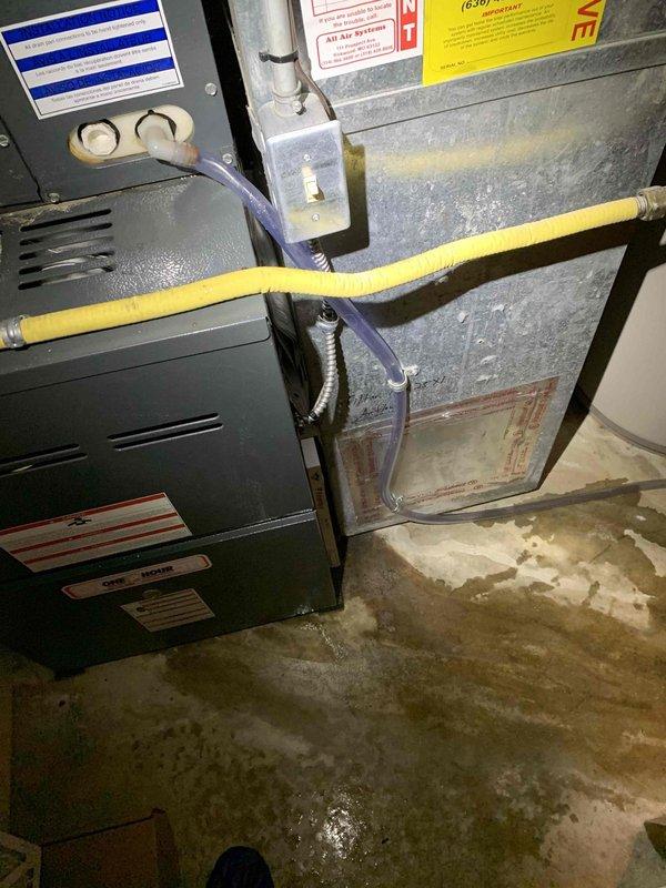 Responded to water leak reported from inside furnace in basement. Upon arrival, found extensive water damage and standing water on concrete floor around 10-year-old HVAC system. Inspected air handler, furnace cabinet, and associated plumbing connections. Identified source of leak and documented conditions with photographs showing water staining, moisture accumulation, and affected equipment including gas line connections and condensate drainage system.