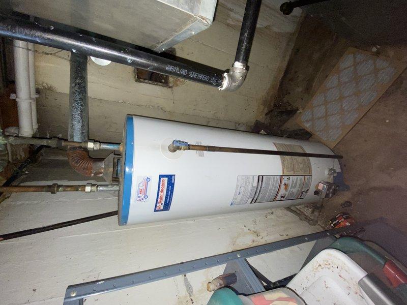 Responded to service call for water heater producing only lukewarm water. Upon inspection of basement utility area, assessed existing water heater condition and determined replacement was necessary. Job temporarily cancelled as installation requires two-person crew due to access constraints and equipment handling requirements. Identified need for sheet metal fabrication to cover existing hole in basement wall prior to installation. Coordinated delivery of new 40-gallon tall gas water heater with 3/4" pressure relief valve to warehouse location. Verified permit requirements with City of University City—no permit sticker required for this installation. Documented existing conditions including aged wooden flooring, concrete block walls, and current plumbing configuration. Photographed existing water heater setup and surrounding utility space for installation planning purposes. Job scheduled for completion upon crew availability and sheet metal preparation.