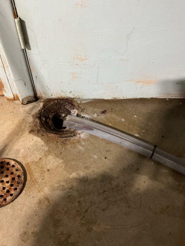 Responded to emergency water leak in basement caused by disconnected A/C condensate drain hose. Upon arrival, found the drain line had become detached from the floor drain, resulting in active water discharge onto the basement floor with visible pooling and moisture damage to the concrete surface. Reconnected the condensate drain hose to the proper drain outlet and secured the connection to prevent future disconnection. Verified proper drainage flow and confirmed the system was operating correctly with no further leakage.