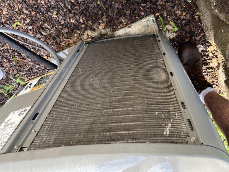 Responded to no cooling complaint on 17-year-old Lennox system. Upon arrival, found outdoor condenser coil heavily obstructed with dirt, debris, and organic matter, severely restricting airflow through fins. Condenser coil cleaning was required to restore proper system operation and airflow. Unit located at ground level in mulched area with significant leaf litter and environmental contamination contributing to restricted airflow condition.
