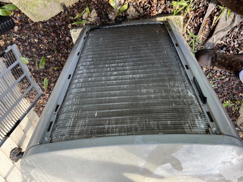 Responded to no cooling complaint on 17-year-old Lennox system. Upon arrival, found outdoor condenser coil heavily obstructed with dirt, debris, and organic matter, severely restricting airflow through fins. Condenser coil cleaning was required to restore proper system operation and airflow. Unit located at ground level in mulched area with significant leaf litter and environmental contamination contributing to restricted airflow condition.