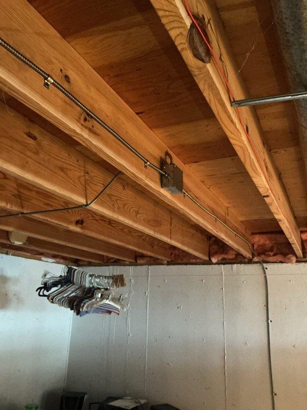 Completed electrical fixture installation in basement area per approved estimate. Installed new electrical wiring through floor joists using appropriate cable routing methods with securing clips and junction boxes. Mounted electrical switch assembly with indicator lights in metallic junction box on foundation wall, utilizing flexible conduit for proper wire protection. All work performed to code specifications with proper grounding and secure mounting hardware.