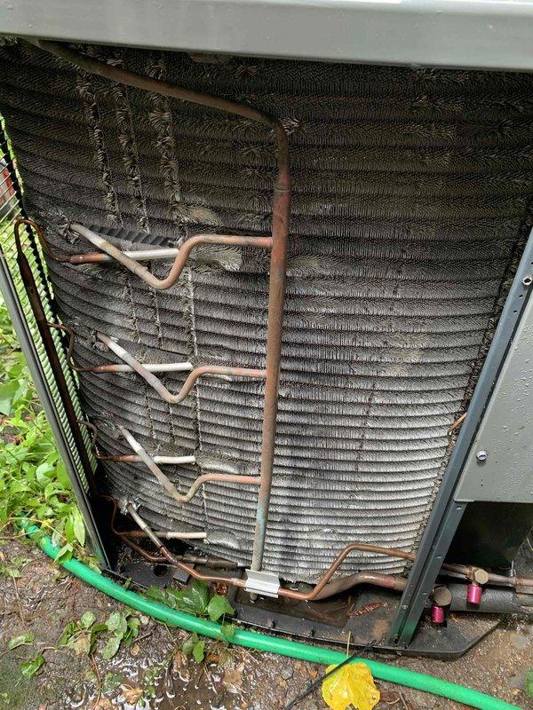 Responded to no-cool call on residential air conditioning system less than 10 years old. Upon arrival, found outdoor condenser unit not operating. Inspection revealed heavily soiled condenser coils with significant accumulation of dirt, dust, and debris restricting airflow through the heat exchanger. Removed side access panel to assess internal components and confirmed extensive buildup on both interior and exterior coil surfaces. Copper refrigerant lines showed signs of normal aging and oxidation. The dense coating on coil fins was impacting system performance and preventing proper heat transfer, which contributed to the unit's failure to operate efficiently. Advised customer to keep unit off and leave fan running until cleaning could be completed to prevent potential compressor damage from reduced airflow conditions.