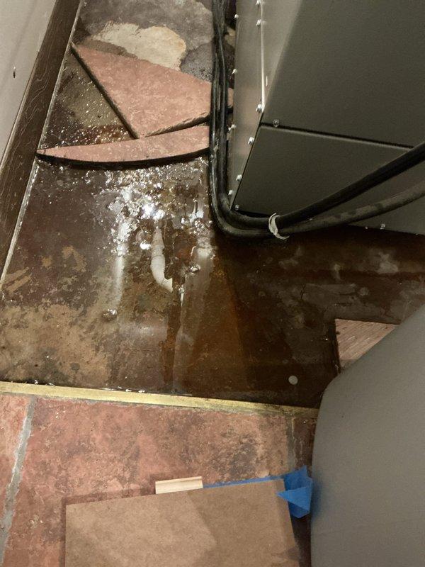 Responded to service call for AC leak requiring location identification. Upon arrival, performed thorough inspection of HVAC system and surrounding areas. Located source of water leak at air handler unit in mechanical space. Found significant water accumulation on floor surfaces and extensive moisture damage to surrounding flooring, walls, and subflooring materials. Confirmed drain line was not source of issue as previously verified by municipal sewer inspection. Inspected humidifier operation and determined it was not contributing factor to ongoing leak. Traced leak to condensate issue at air handler unit. Documented extensive water damage including deteriorated flooring tiles, wall discoloration, and moisture infiltration in crawlspace area beneath unit. Photographed conditions showing standing water, damaged subflooring, compromised wall surfaces, and affected ductwork area. Identified primary leak source and provided recommendations for necessary repairs to resolve water intrusion 