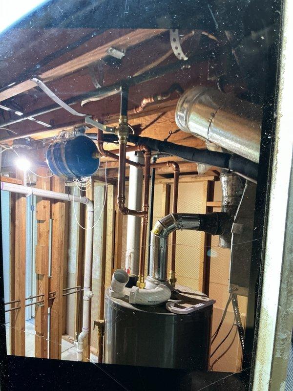 Completed comprehensive plumbing installation and code compliance upgrade involving replacement of deteriorated cast iron waste piping with PVC throughout crawl space and vertical stack serving multiple fixtures, installation of proper venting system from basement bathroom through first floor, and water heater code upgrades including expansion tank, T&P valve, and gas line modifications. Replaced cast iron and improperly installed PVC drain lines in crawl space for kitchen and laundry with code-compliant piping and hangers, removed and replaced defective cast iron stack above basement floor serving two bathrooms including tub, shower, two lavatories and two water closets. Additional work included installation of pressure reducing valve regulator, wire stress clamp for garbage disposal power supply, removal and capping of flexible gas connector to exterior grill, and installation of 2-inch and 1.5-inch vent piping from basement bathroom reconnecting to first floor vents, all performed u