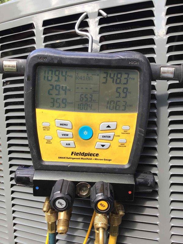 Responded to service call for error code displaying on Trane thermostat at front entrance foyer unit. Upon arrival, connected refrigerant manifold and micron gauge to assess system pressures and temperatures, which revealed abnormal readings indicating potential refrigerant or airflow issues. Inspection of outdoor unit discovered significant rust and corrosion on rigid ductwork connections, compromised condensate drainage system with standing water and debris accumulation in drip pan, and deteriorated flexible duct insulation with visible environmental contamination. Documented equipment condition with diagnostic measurements and photographic evidence for repair recommendations.