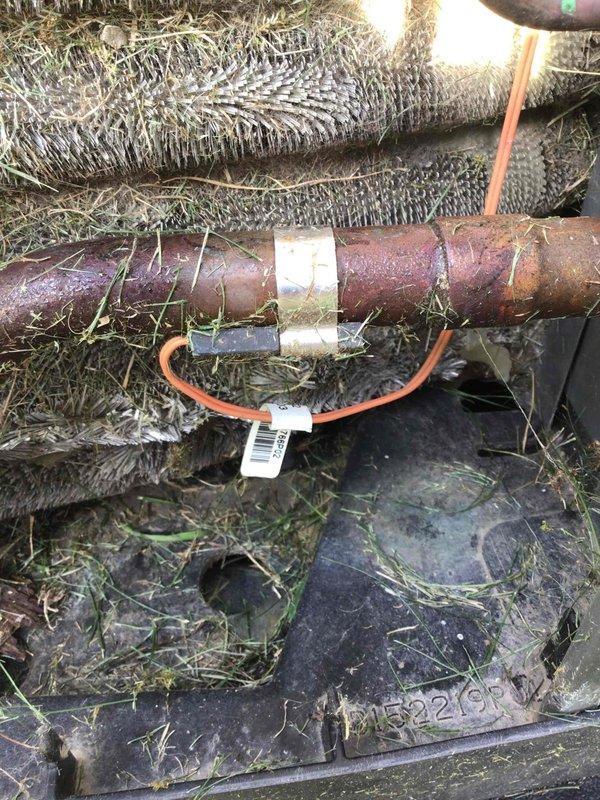 Responded to service call for error code displaying on Trane thermostat at front entrance foyer unit. Upon arrival, connected refrigerant manifold and micron gauge to assess system pressures and temperatures, which revealed abnormal readings indicating potential refrigerant or airflow issues. Inspection of outdoor unit discovered significant rust and corrosion on rigid ductwork connections, compromised condensate drainage system with standing water and debris accumulation in drip pan, and deteriorated flexible duct insulation with visible environmental contamination. Documented equipment condition with diagnostic measurements and photographic evidence for repair recommendations.