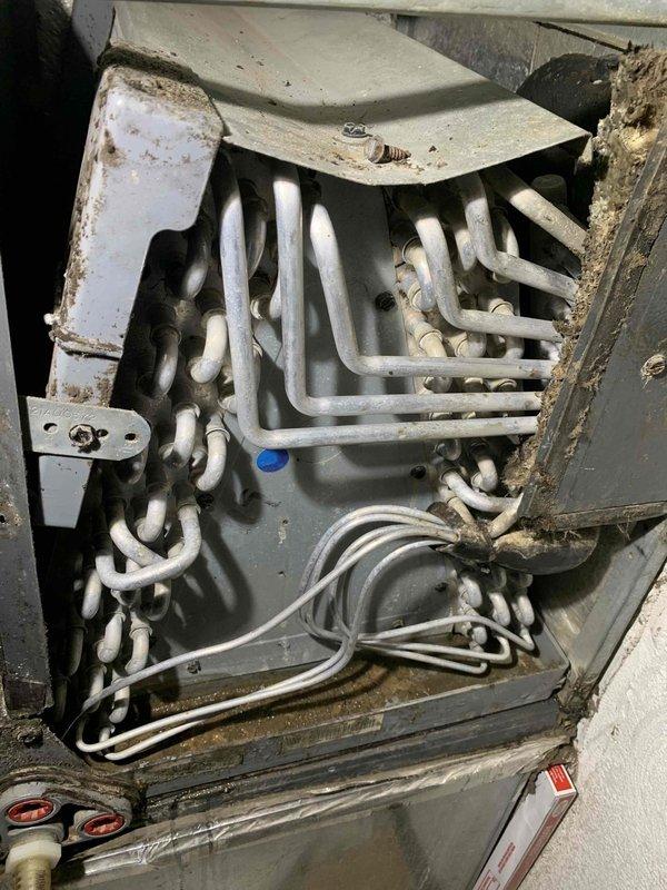 Responded to report of water leaking near furnace affecting flooring. Upon inspection, found evaporator coil assembly with significant dirt and debris accumulation, indicating restricted airflow and potential condensate drainage issues. Photographed interior compartment showing dirty coil with dust buildup on heat exchanger surfaces and visible deterioration of surrounding components. Observed condensate management system and confirmed water intrusion had occurred on laminate flooring in utility area. Per customer instruction, shut down air conditioning system and left fan in continuous operation to prevent further water damage while awaiting repair authorization.