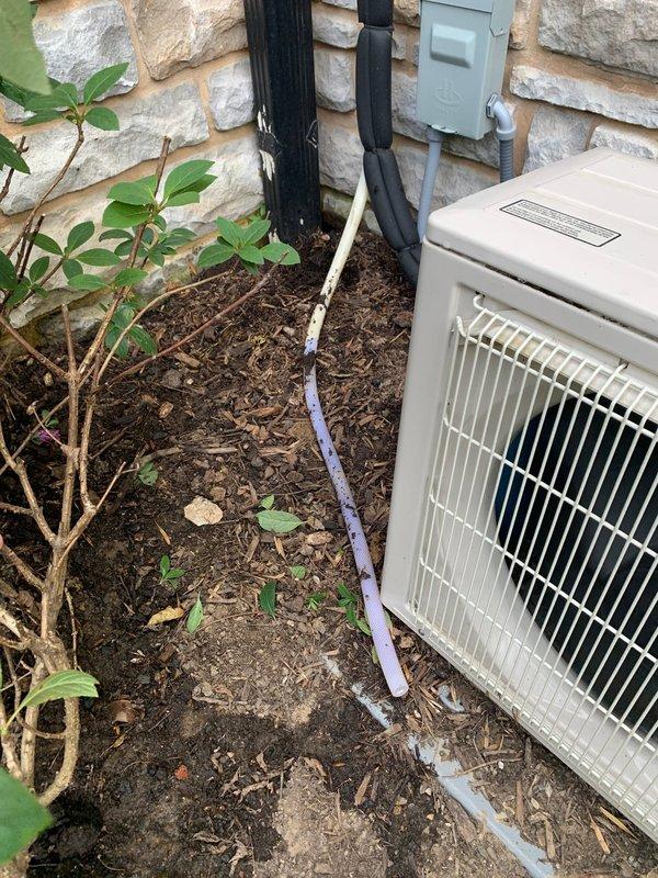 Responded to service call for Mitsubishi mini split system in room above garage blowing warm air. Upon arrival, performed diagnostic evaluation of outdoor condensing unit and indoor air handler. Inspected refrigerant line set, electrical connections, and condensate drainage system. Unit was originally installed by unknown contractor. Documented equipment condition with photos showing outdoor unit placement against exterior wall with line set routing and electrical disconnect panel. Identified issues preventing proper cooling operation and provided repair recommendations to restore system functionality.