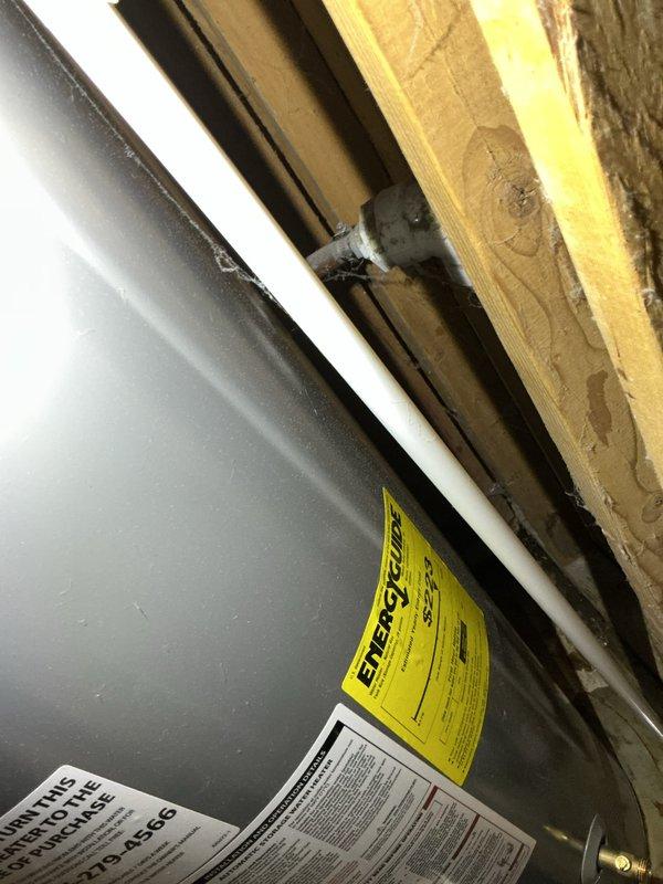 Responded to emergency water leak call with AC system flooding above downstairs furnace. Upon arrival, found excessive condensate water accumulation requiring towel changes every one to two hours. Inspected 10-year-old ground-level outdoor unit and traced source to condensate drainage issue in attic ductwork and plenum area. Examined HVAC system components including air handler, ductwork connections, and condensate drain lines. Identified blockage or improper drainage causing water overflow from drain pan. Cleared condensate line obstruction and verified proper drainage flow. Inspected surrounding areas including water heater and furnace for any secondary water damage or related issues. Tested system operation to ensure condensate removal functioning correctly and no further leaking present. Documented equipment conditions and repair work with photographs of attic plenum assembly and utility area showing furnace and adjacent equipment.