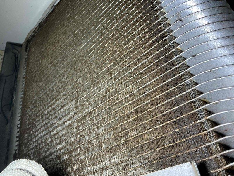Responded to callback regarding inadequately cleaned filters and clogged evaporator coil on hallway unit. Upon inspection, found evaporator coil heavily contaminated with dust, dirt, debris, and hair buildup throughout aluminum fins, significantly restricting airflow. Coil showed extensive accumulation between fin spaces, particularly in center and lower sections, causing reduced system performance. Documented coil condition with photographs showing dark discoloration and blockage throughout heat exchanger assembly. Addressed customer concerns regarding maintenance quality and provided guidance on proper cleaning procedures for severely impacted coil assembly.