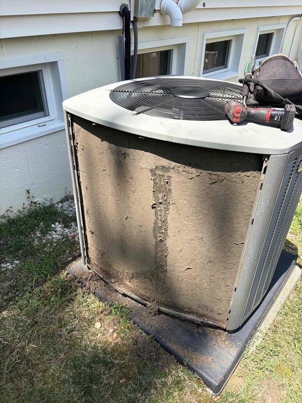 Responded to no cooling complaint on 10+ year old ground-level condensing unit. Upon arrival, performed diagnostic evaluation using refrigerant manifold gauge, which revealed system pressures of 379.8 psig on high side with 11.4°F subcooling and 44.5°F suction temperature. Unit exterior showed significant dirt and debris accumulation from extended service life, indicating need for thorough cleaning to restore proper airflow and heat transfer efficiency.
