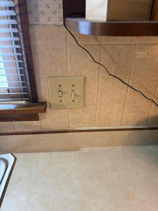 Responded to reported non-functioning kitchen switch controlling garbage disposal and light fixture. Upon arrival, inspected dual-switch configuration mounted on tiled backsplash area. Tested both toggle switches for proper operation and continuity. Verified electrical connections at switch box, checked wire terminations, and ensured proper grounding. Inspected associated circuits at main electrical panel to confirm breaker status and proper power supply to kitchen circuits. Troubleshot switching mechanism and load connections to identify failure point in control circuit.