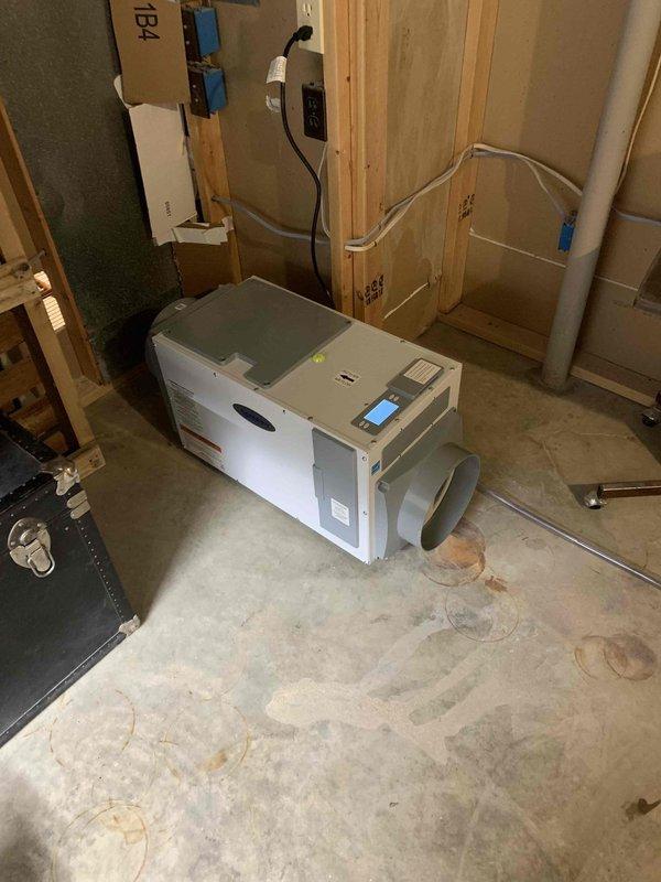Installed freeze stat on new HVAC unit and completed dehumidifier installation in unfinished basement area. Dehumidifier was positioned on concrete floor with ductwork connection and wall-mounted digital control panel displaying humidity readings and operational status. Documentation photos of equipment serial number and installed system were captured per service requirements.