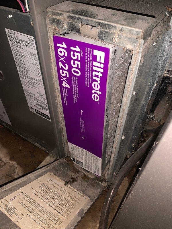 Responded to report of excessive water leakage from 10-year-old basement air handler unit with water migration to adjoining room causing carpet saturation and strong odor. Upon arrival, inspected indoor air handler and found active condensate drainage issue. Examined outdoor condenser unit coil, noting significant dirt and debris accumulation on fins requiring attention. Inspected air handler cabinet and confirmed Filtrete 1550 filter (16x25x4) in place with visible dust buildup on housing. Documented equipment condition with photos showing soiled condenser coils and filter assembly area. Identified condensate system malfunction as source of water leakage affecting basement flooring and adjacent carpeted area.